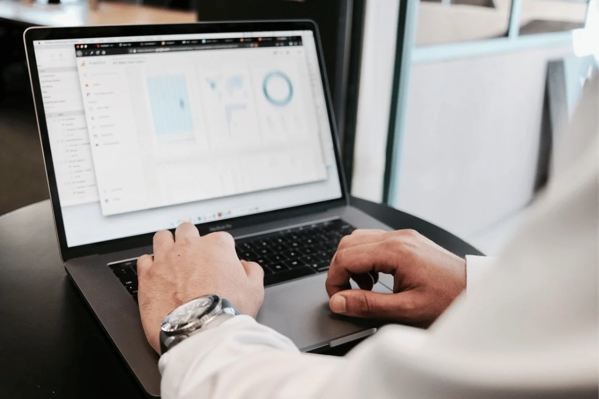 Close-up of hands reviewing analytics charts on a MacBook.
