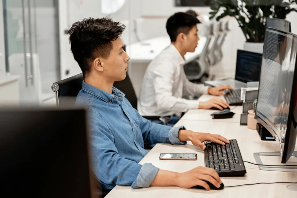 Developers working at desktop computers in a modern tech office.