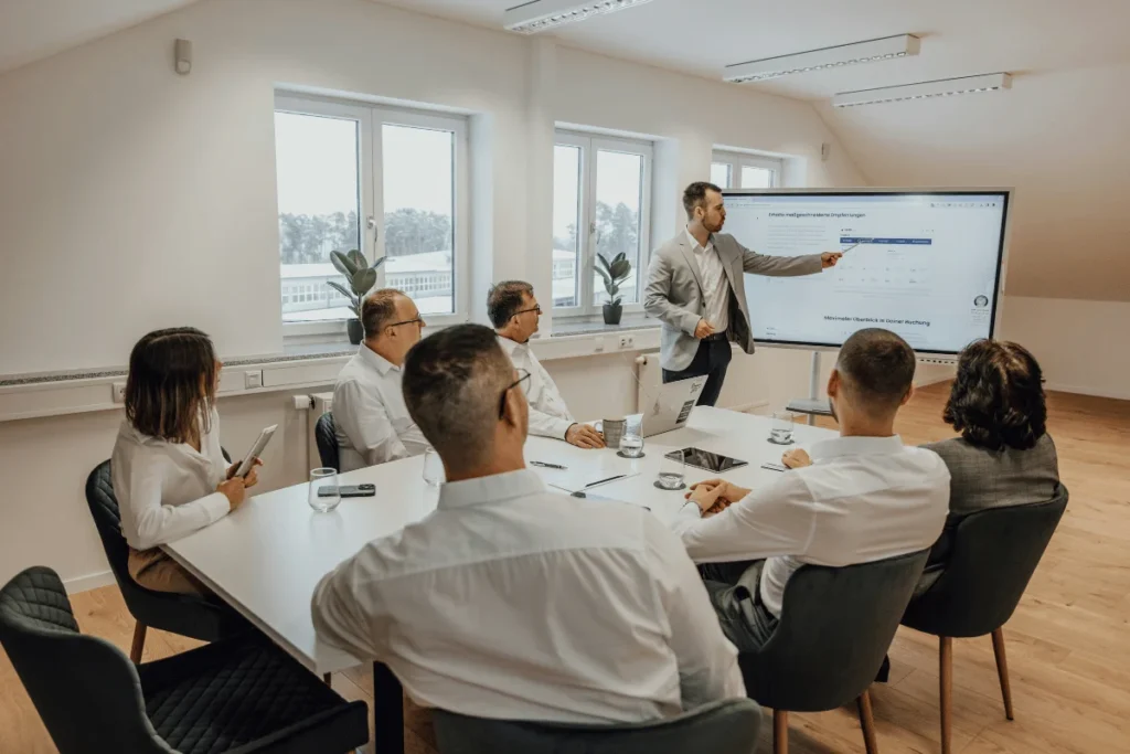 Business team watching a presentation on a large screen in meeting room.