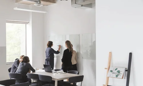 Business professionals mapping ideas on whiteboard.