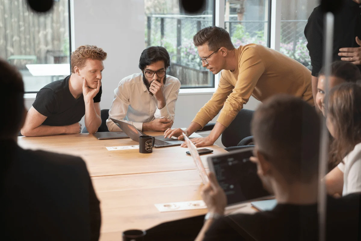 Team collaborating around a laptop during a meeting.