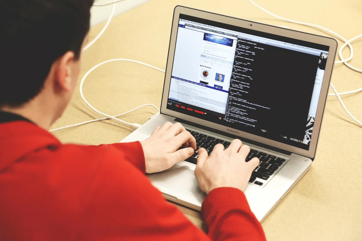 Developer coding on a MacBook Pro with website open on screen.