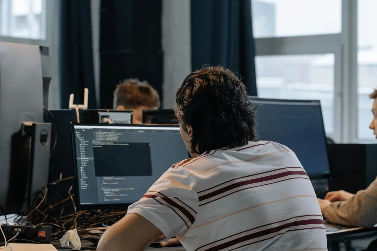 Developer working on code in a multi-monitor setup at the office.