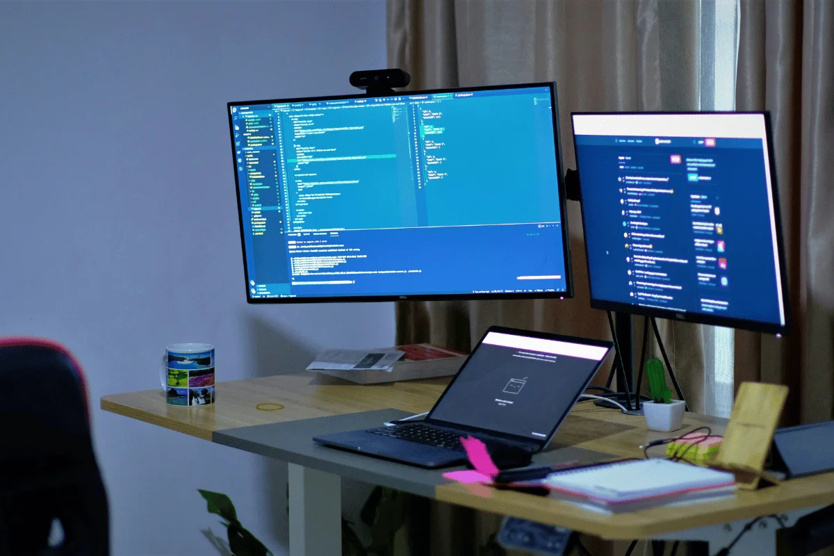 Triple-monitor coding setup with open source code on screen.