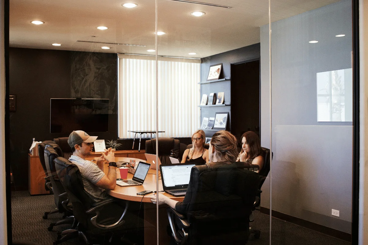 Team meeting in a glass-walled conference room.