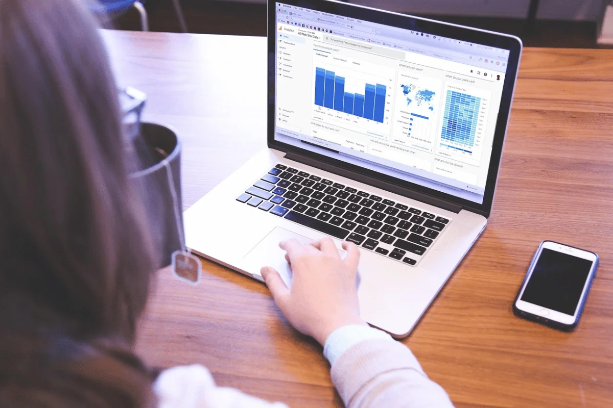 A person uses a laptop displaying graphs and charts, suggesting data analysis.
