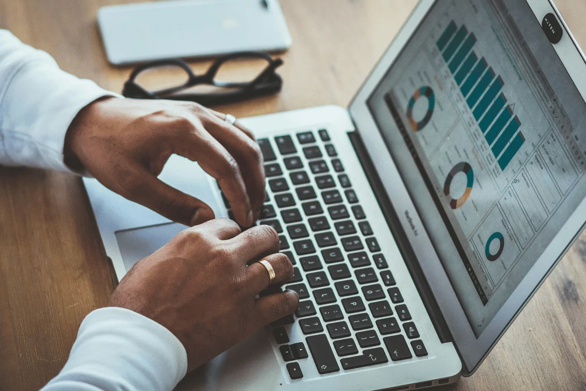 Hands typing on laptop displaying business analytics dashboard.