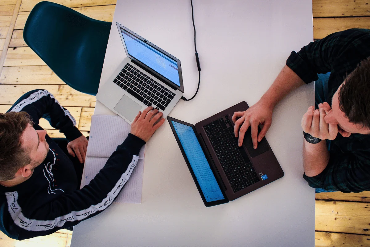 Overhead view of team collaboration using laptops and notes.