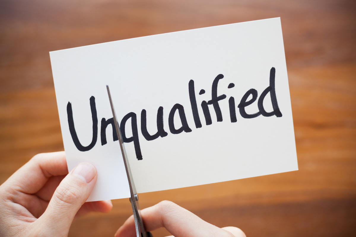 person cutting paper with the word "unqualified" 