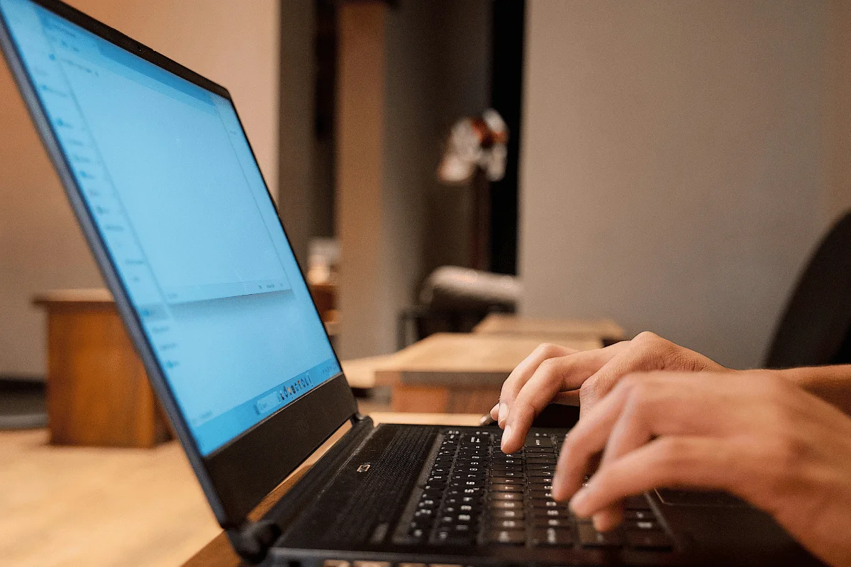 Close-up of hands typing on a laptop keyboard.