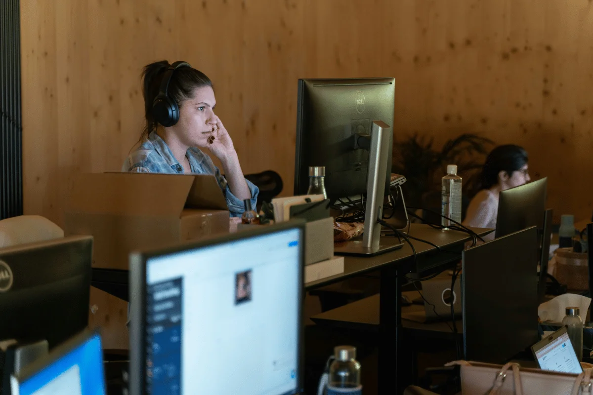 Woman wearing headphones working at computer in office.