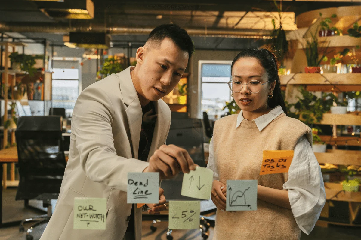 Team collaborating with sticky notes on office glass wall.