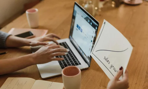 Hand using laptop with project management dashboard open.